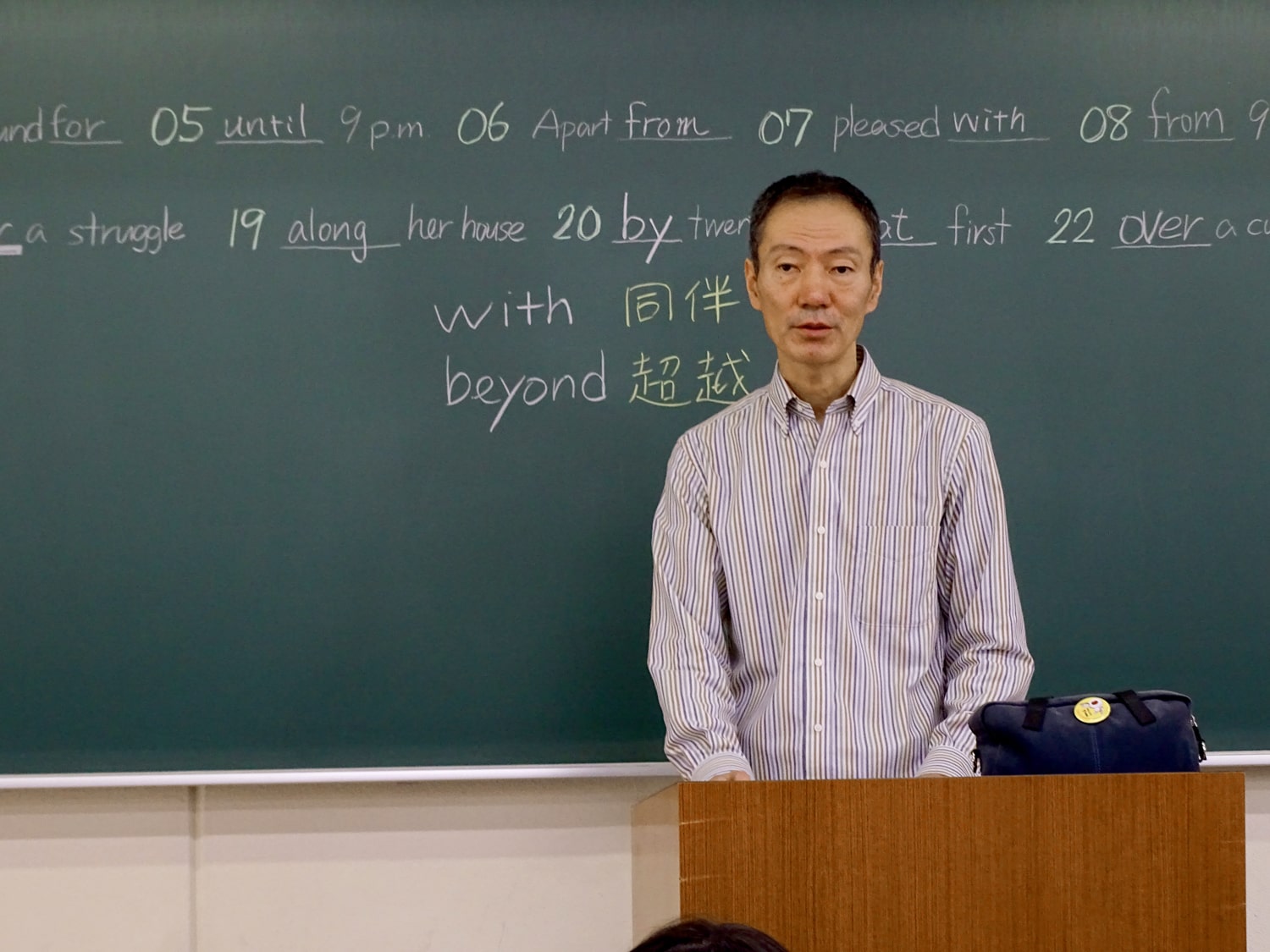 黒板の前で授業を行う岡山進研学院の英語・小論文講師：堀川由満